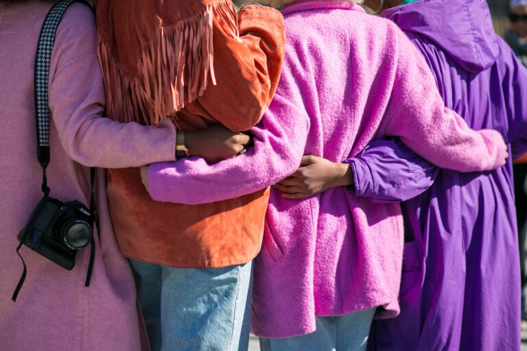 Mulheres se abraçam com diferentes cores de casacos.
